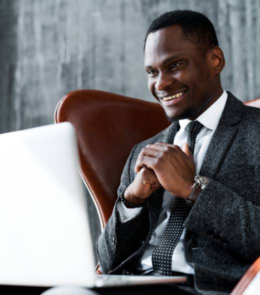 Smiling,Dark-skinned,Businessman,In,A,Suit,Sitting,In,An,Office